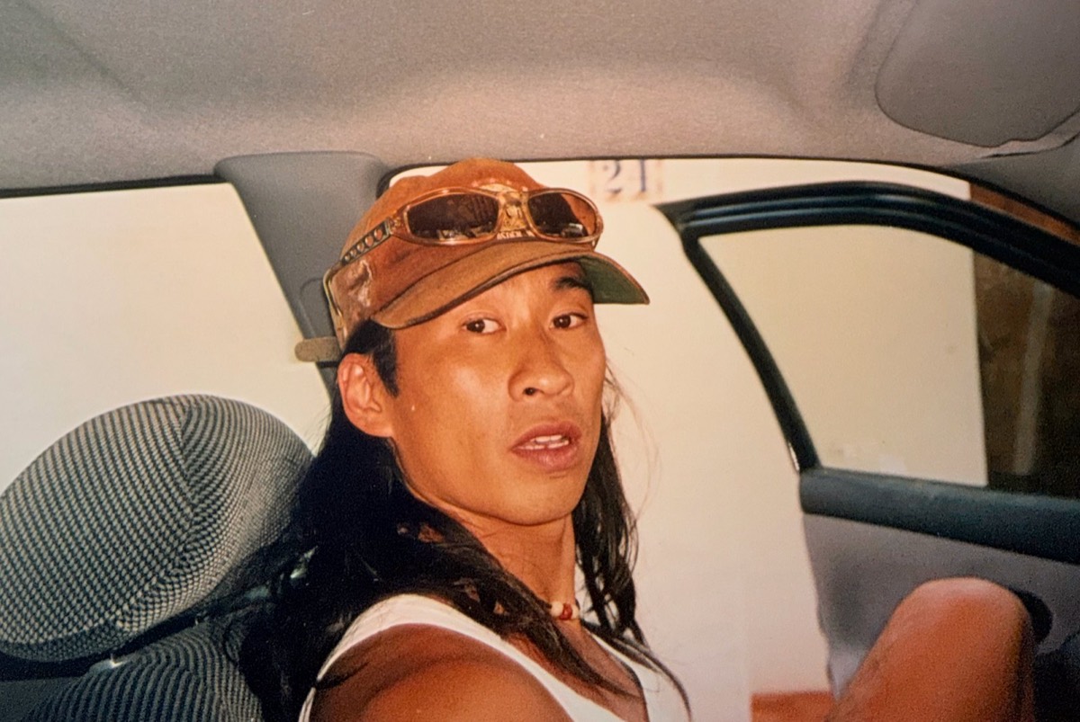 Wilson in a car, cap and goggles, long hair